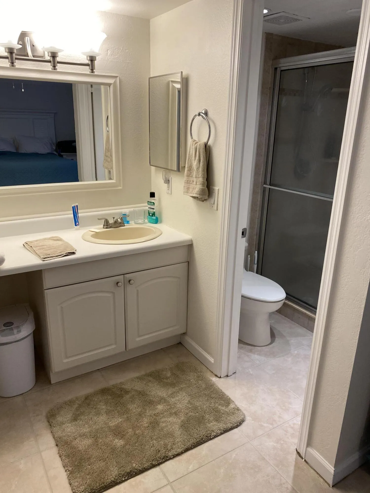 White vanity cabinetry with a built-in sink, wall-mounted mirror, and tile flooring