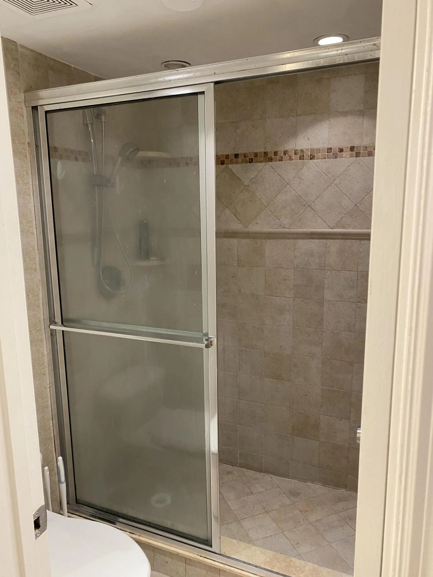Enclosed shower with tiled walls and decorative accent band