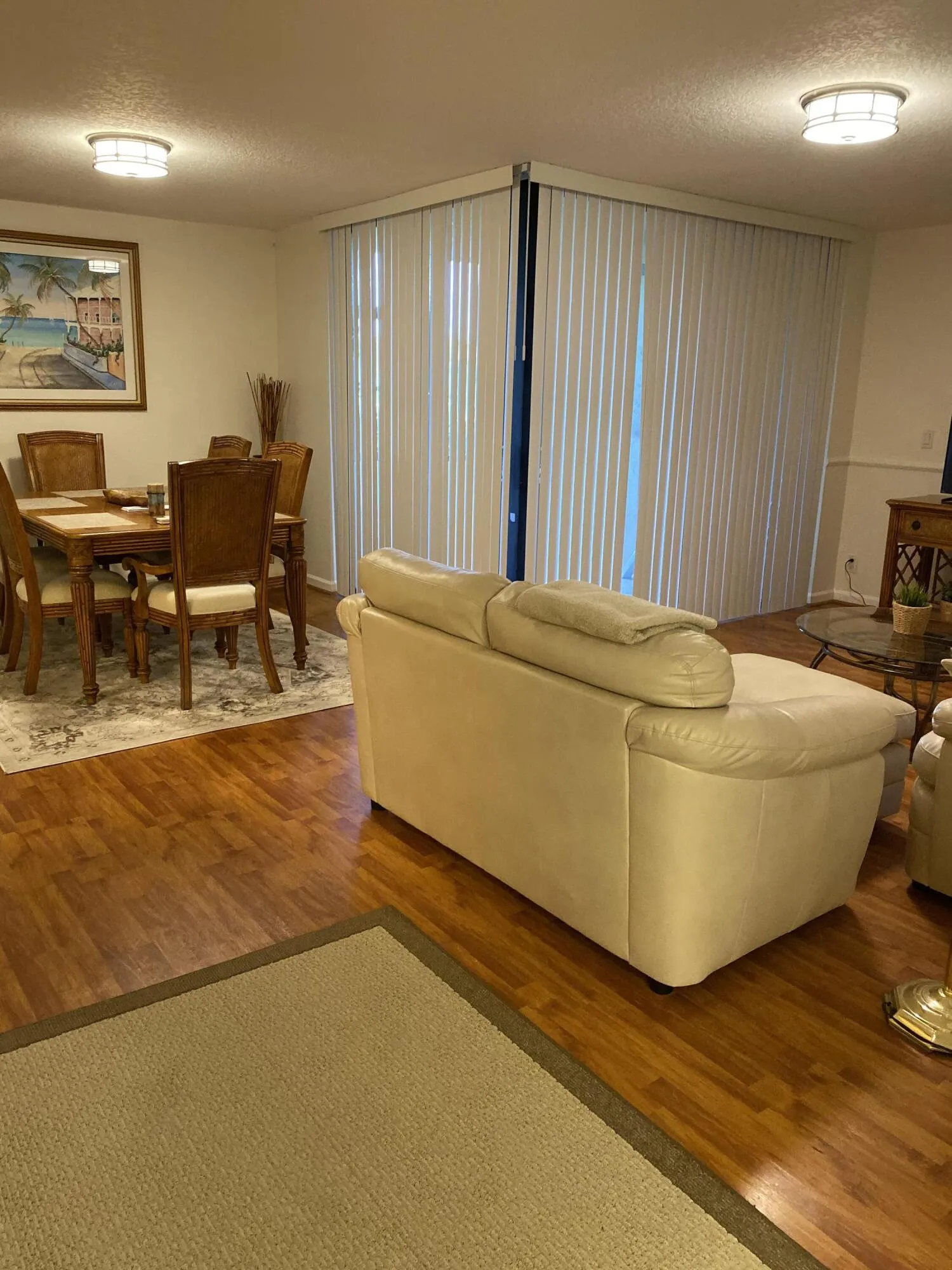 Hardwood-finish flooring throughout, featuring a large window with horizontal blinds, and recessed lighting