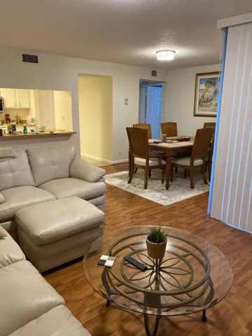 Wood-finish flooring throughout, with a dining area featuring a light-toned ceiling and a wall-mounted light fixture