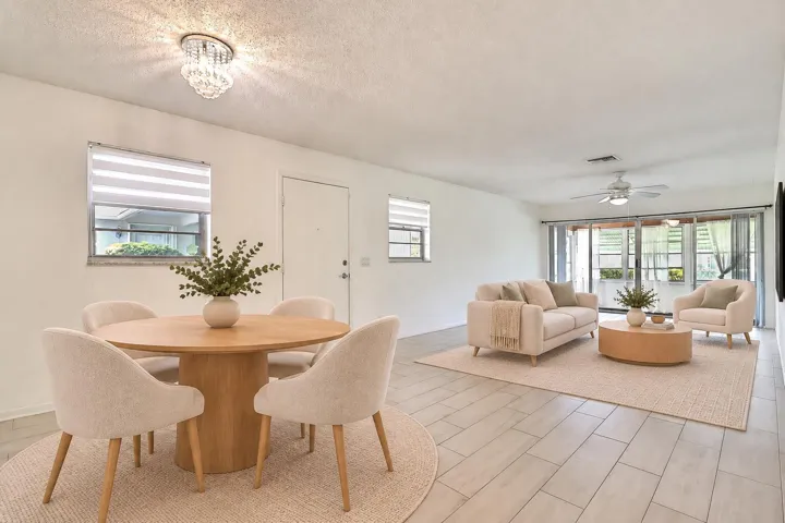 Spacious living area featuring tile flooring, a built-in ceiling fan, and sliding glass doors