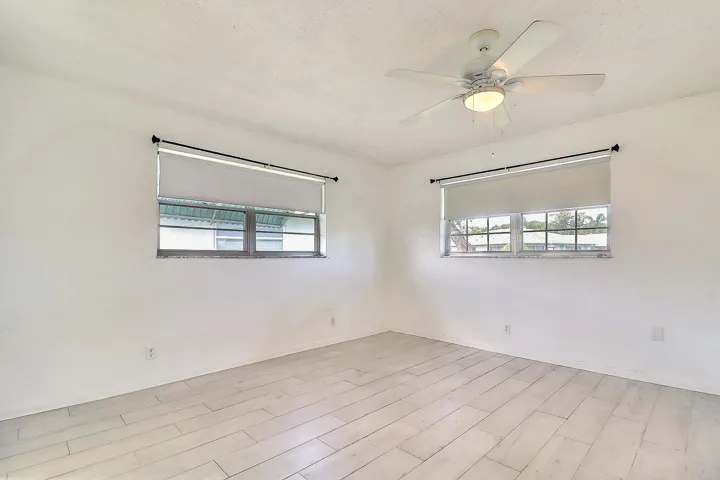 Recessed windows with roller shades, a ceiling fan with integrated lighting, and wood-finish flooring