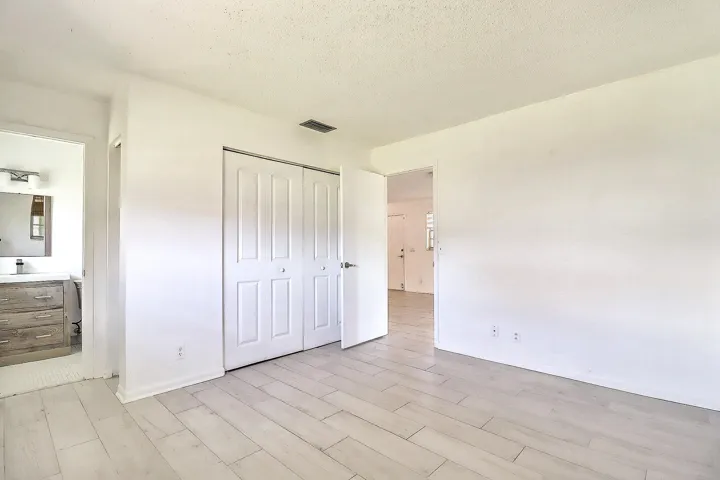 Room featuring light wood-finish flooring, white walls, and a built-in closet with bi-fold doors