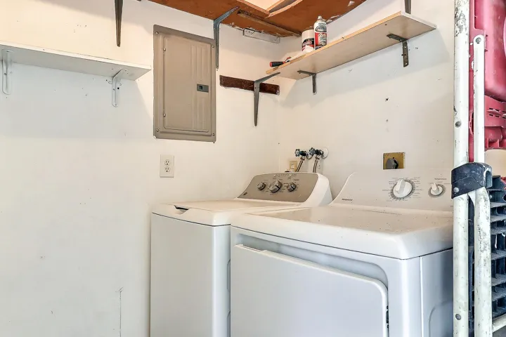 White walls featuring exposed ceiling joists and mounted shelving