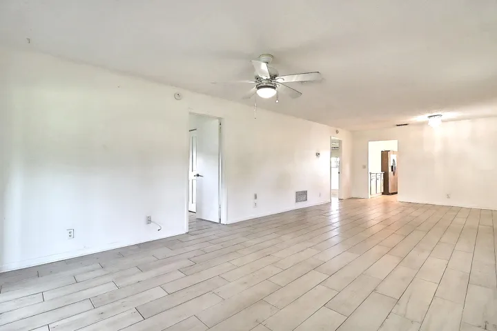 Spacious interior featuring wood-finish tile flooring, recessed lighting, and a ceiling fan with integrated lighting