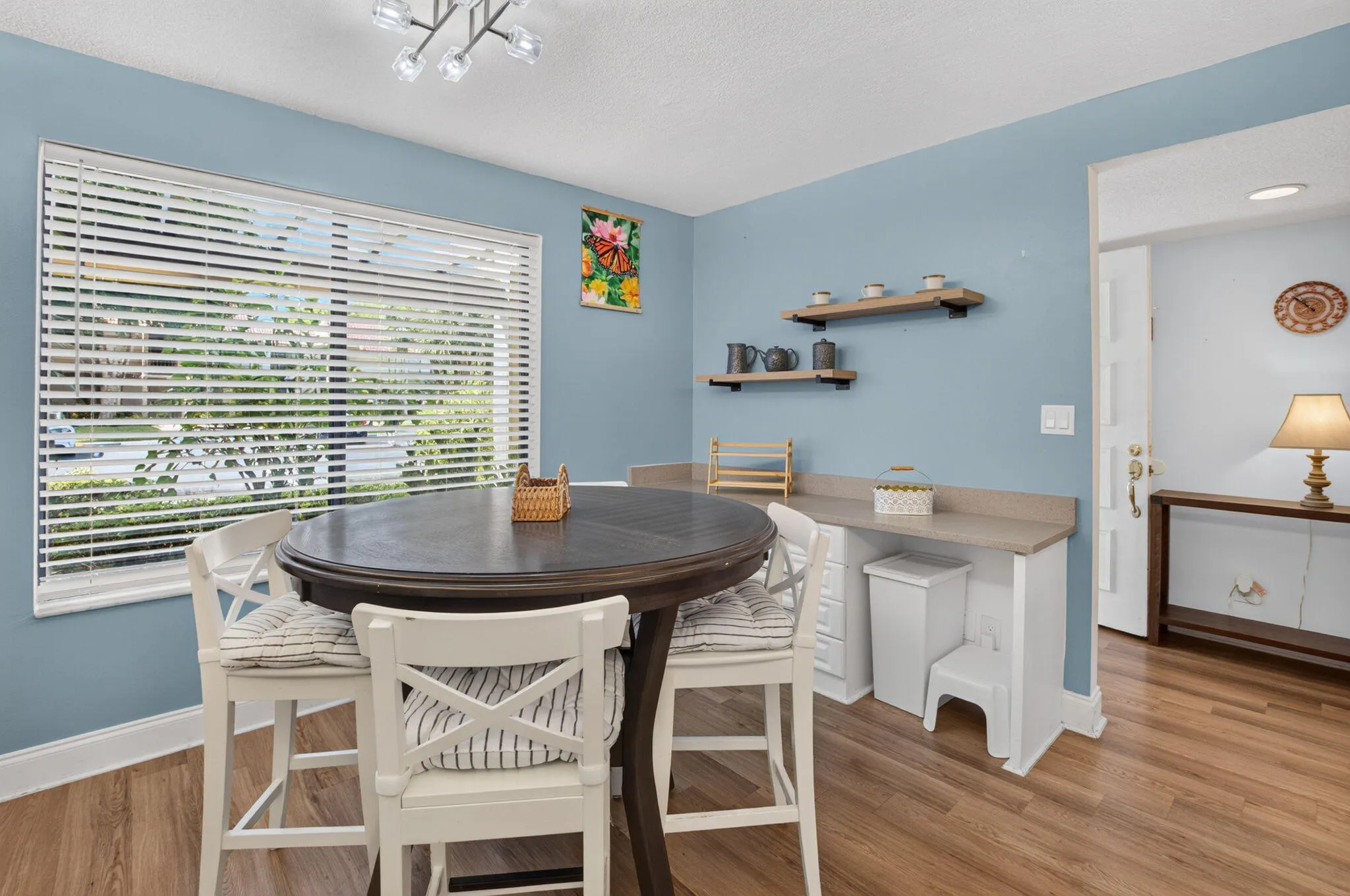 Expansive window with horizontal blinds, and wood-finish flooring
