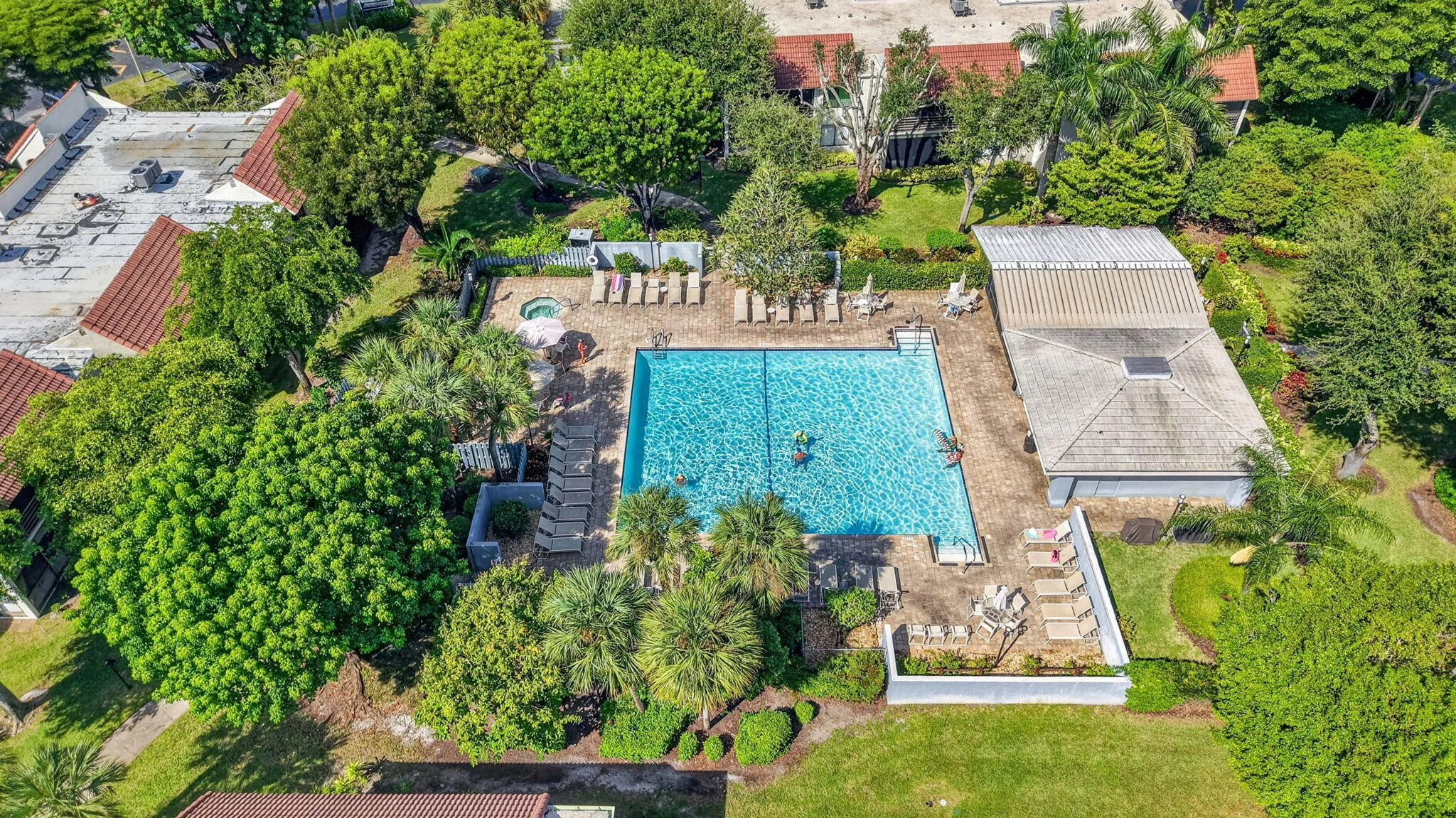 Expansive outdoor pool area featuring a large rectangular pool, a separate hot tub, and a surrounding paver deck