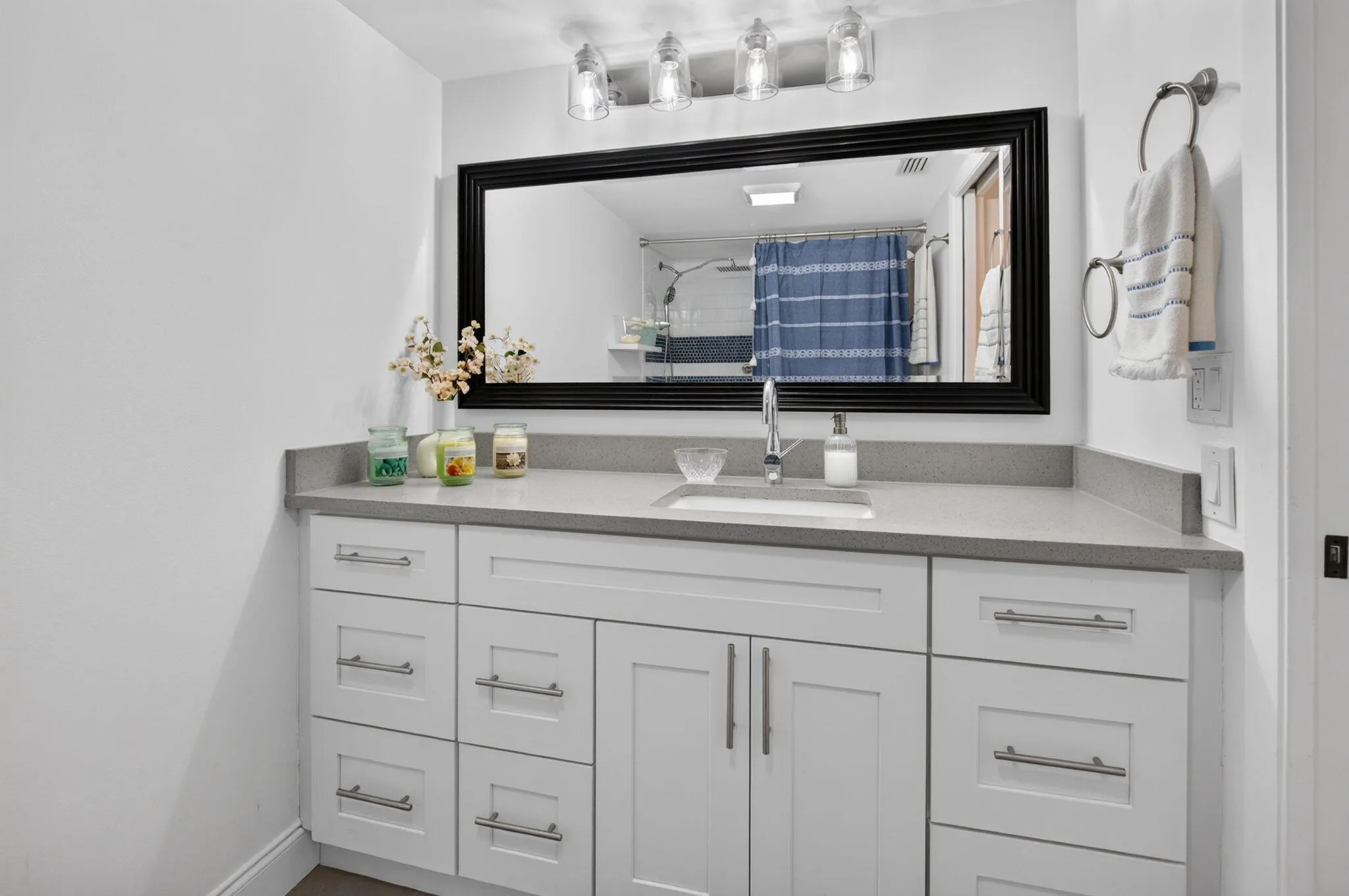 White vanity with shaker-style cabinetry, a built-in rectangular sink, and a countertop