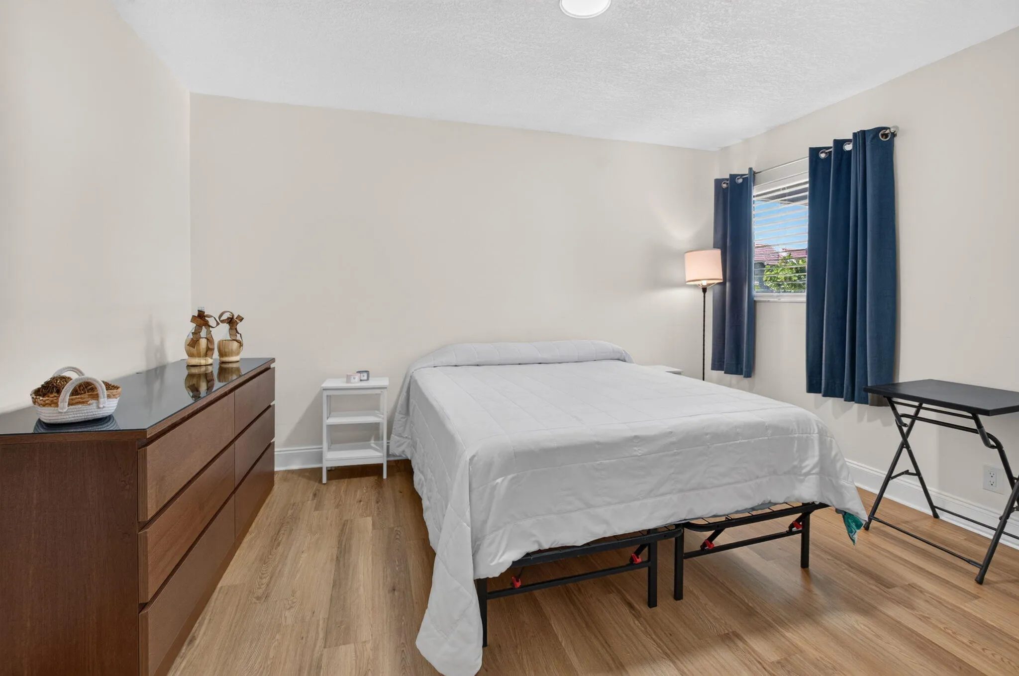 Wood-finish flooring, white walls, and a window with blinds
