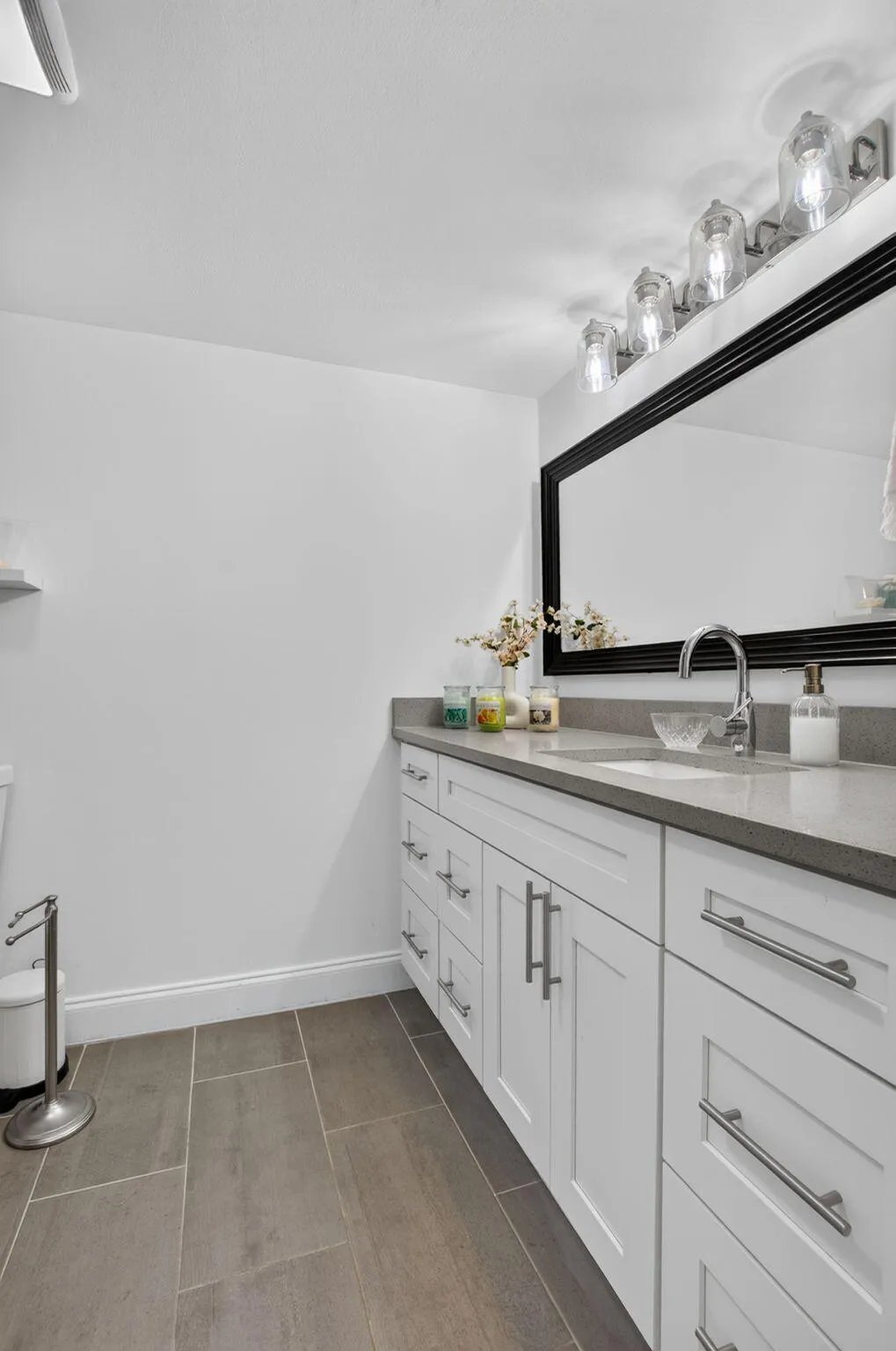 White shaker-style vanity with ample storage, integrated sink, and dark countertop