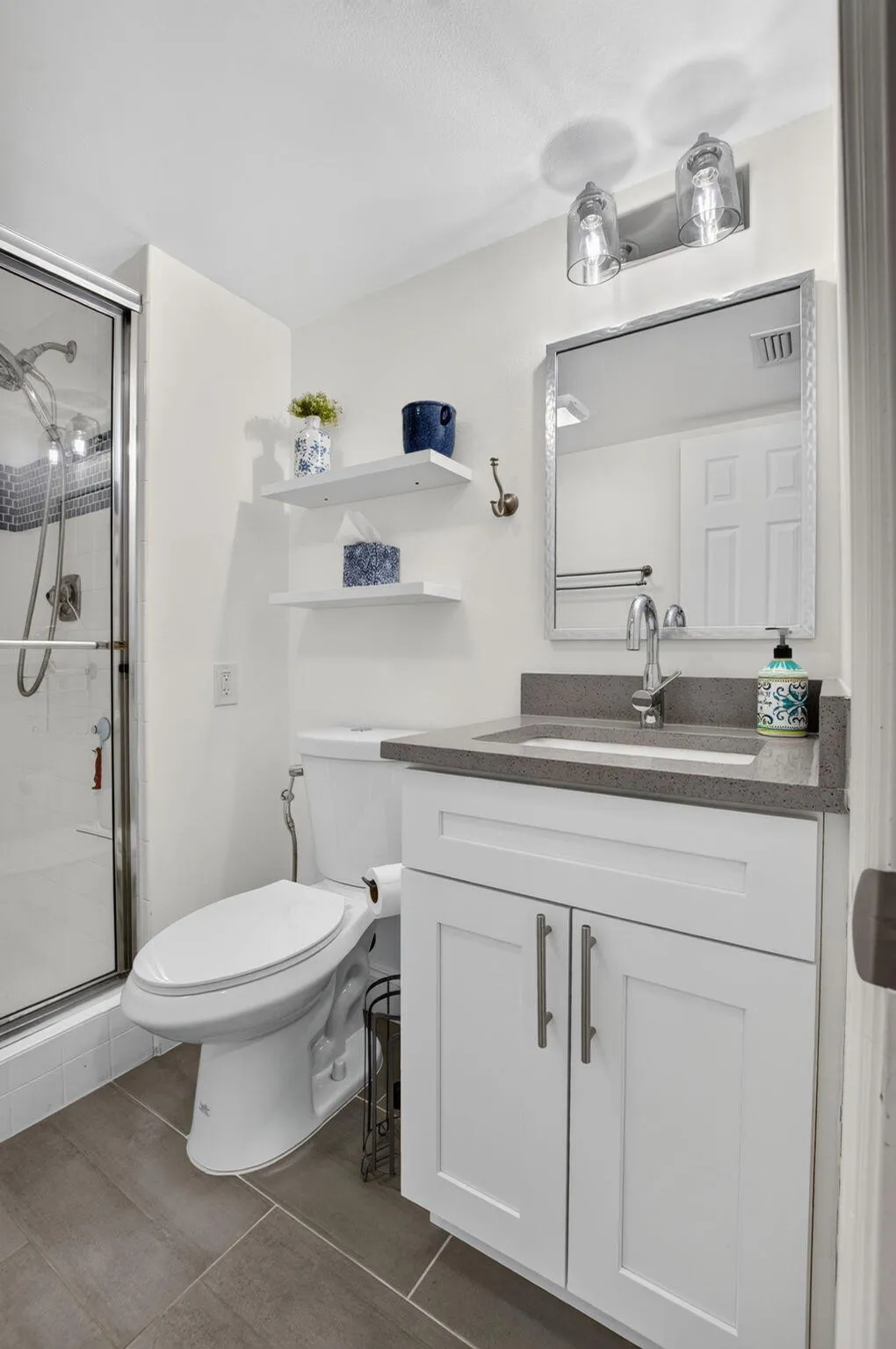 White vanity with shaker-style cabinetry, quartz countertop, and an undermount sink