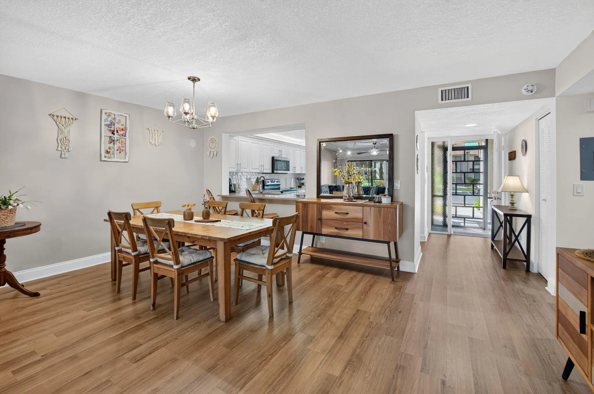 Wood-finish flooring throughout, dining area with a contemporary chandelier, pass-through window to the kitchen