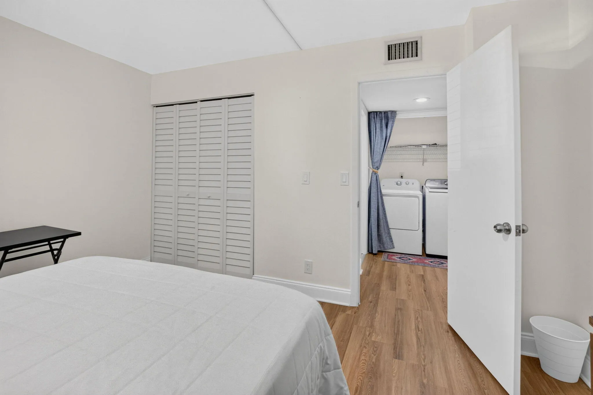 Wood-finish flooring throughout, white louvered bifold closet doors, and an in-unit laundry area featuring a washer and dryer