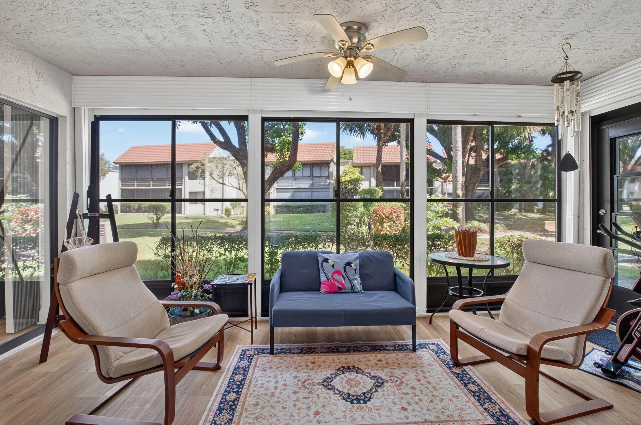 Sunroom featuring multiple large windows, a ceiling fan with light fixture, and wood-finish flooring