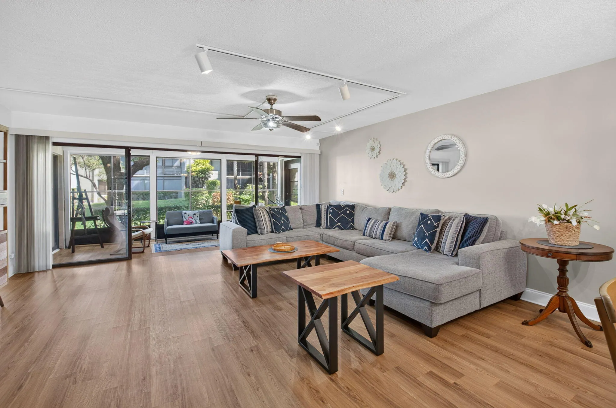 Expansive living area featuring wood-finish flooring, a ceiling fan, and track lighting
