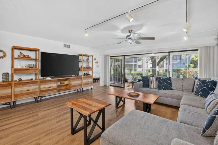 Spacious living area featuring wood-finish flooring, track lighting, and a ceiling fan
