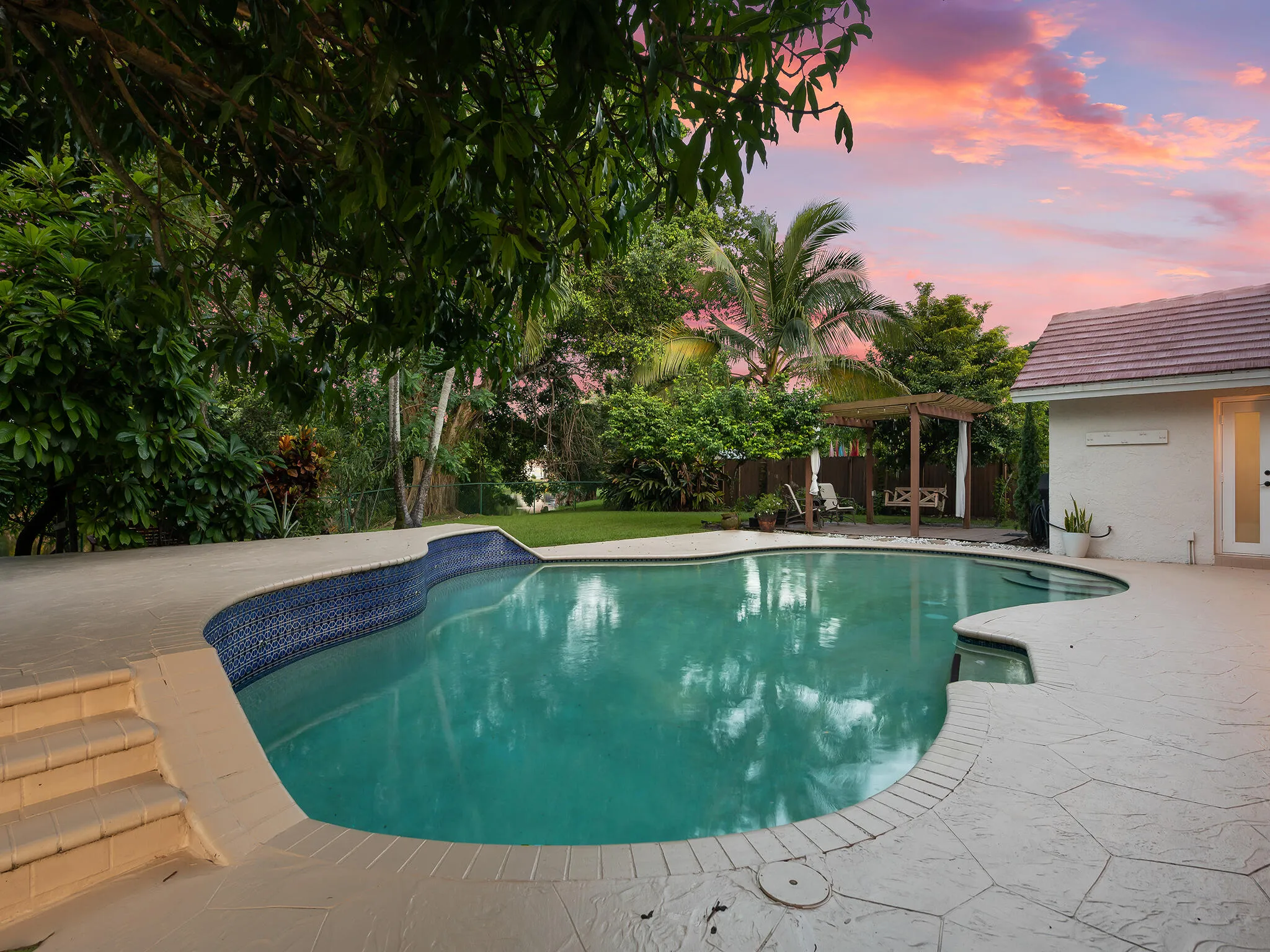 Stone pool decking with tropical greenery.