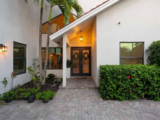 Covered entry tucked under mature tropical shade.