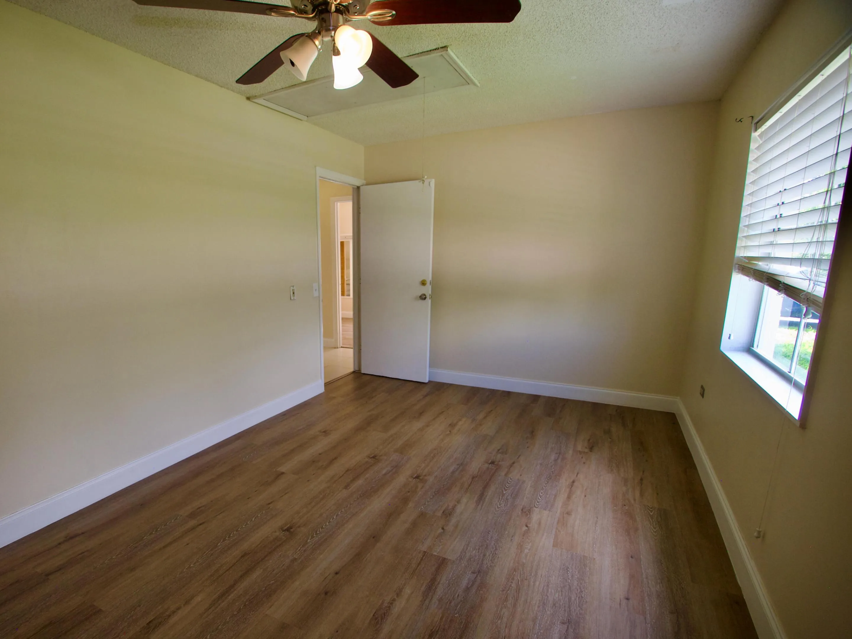 Wood-finish flooring, ceiling fan, natural light from a window with blinds, and neutral wall tones