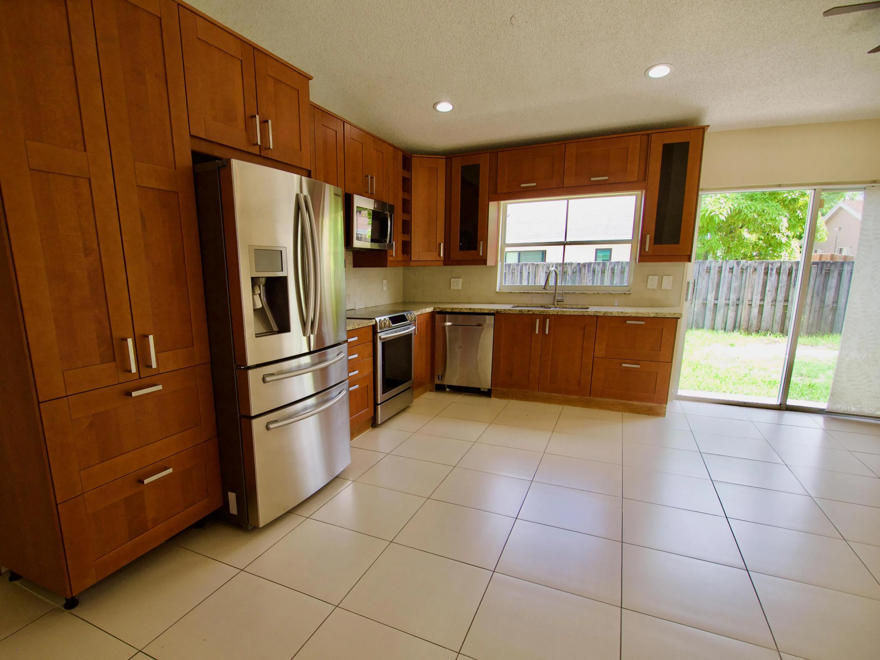 Kitchen featuring wood-finish cabinetry, stainless steel appliances, light-toned countertops, and tile flooring