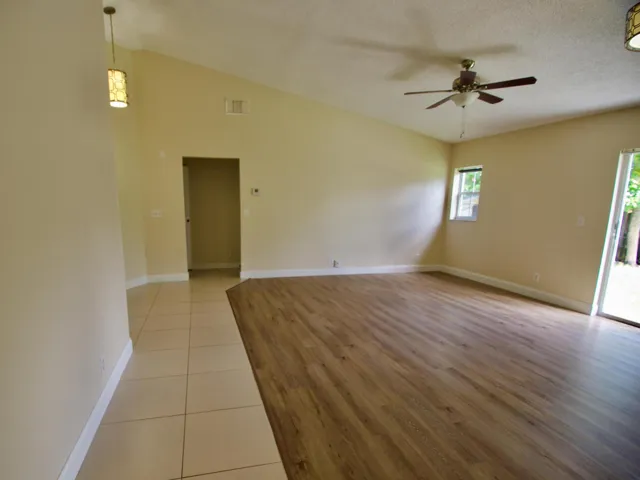 Vaulted ceiling, wood-finish flooring, ceramic tile flooring, ceiling fan, and sliding glass door