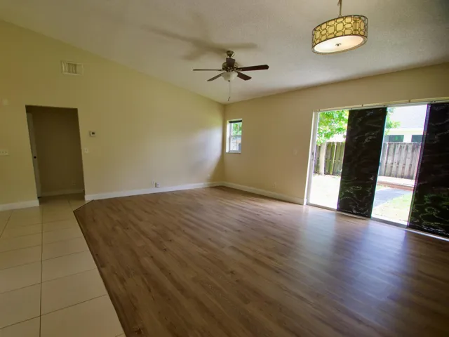 Vaulted ceiling, wood-finish flooring, ceramic tile flooring, ceiling fan, and sliding glass doors