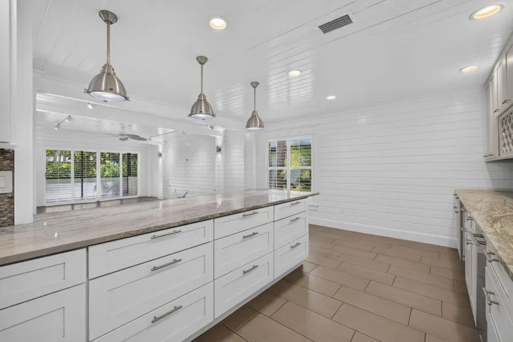 Kitchen featuring white shaker-style cabinetry, light-toned countertops, recessed lighting, and wood-finish flooring