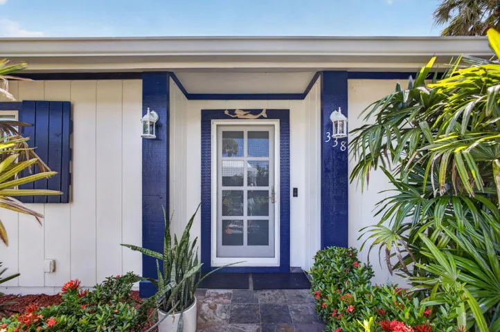 Freshly painted White vertical siding with blue trim accents, a glass-paneled entry door