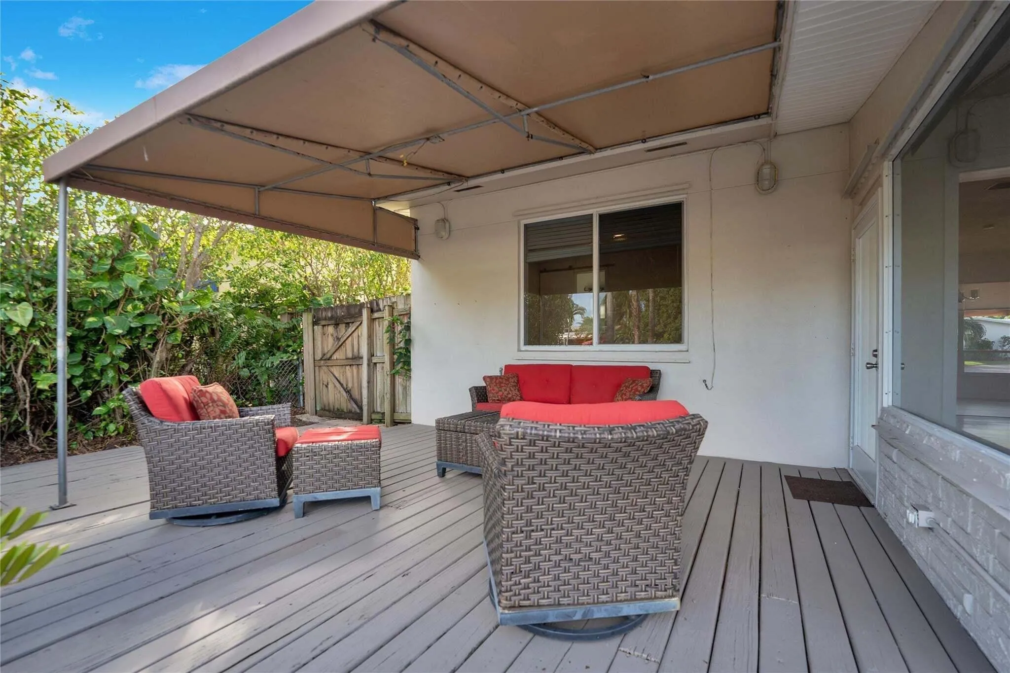 Virtually staged. Covered outdoor patio featuring a wood-finish deck and mature landscaping