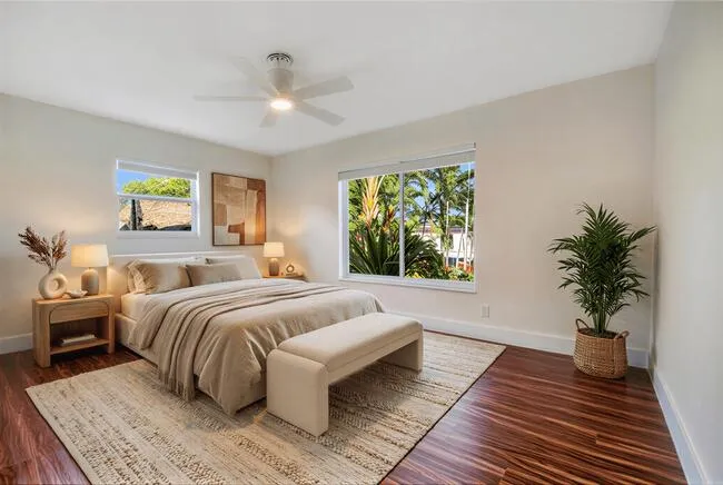 Virtually staged. Rich wood-finish flooring, white walls, and a ceiling fan with integrated lighting