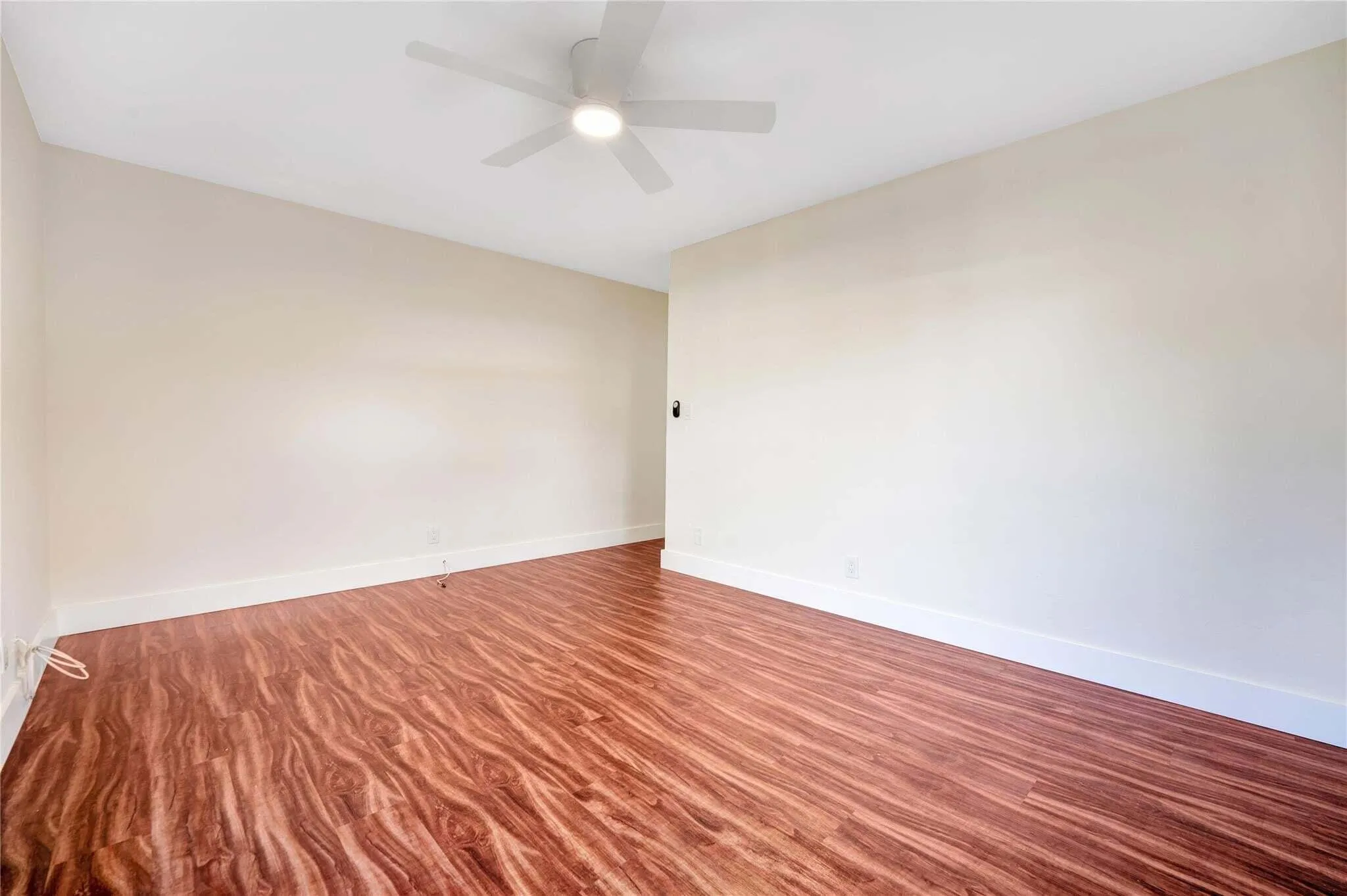 Wood-finish flooring, white walls, and a ceiling fan with integrated lighting