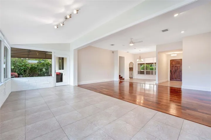 Expansive main living area featuring tile flooring, wood-finish flooring, recessed lighting, and a white paneled entry door
