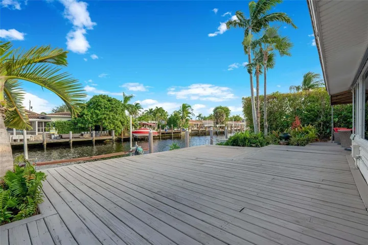Expansive waterfront decking with direct canal access, mature palm trees, and lush landscaping