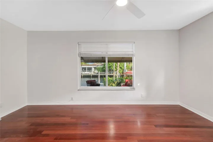 Wood-finish flooring with a window offering canal views, featuring a ceiling fan and horizontal blinds