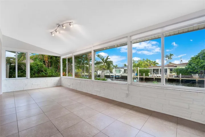 Room featuring expansive windows, tile flooring, white brick-finish walls, and a track lighting fixture