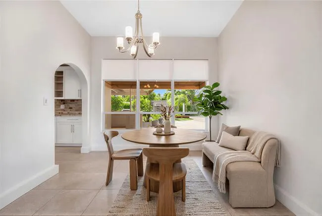 Virtually Staged. Recessed window with exterior scenery, contemporary chandelier, tiled flooring and arched doorway