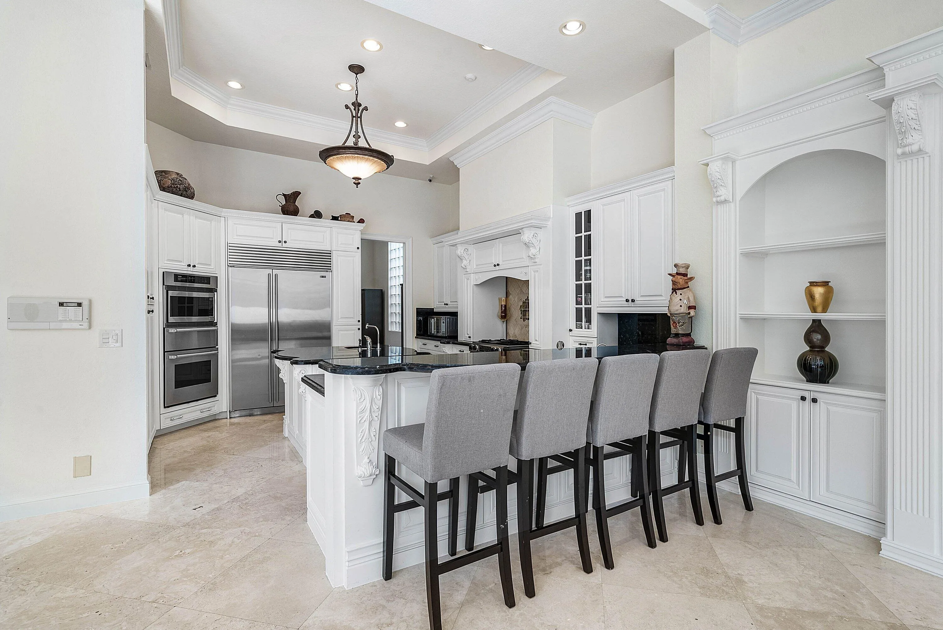 Gourmet kitchen with stainless steel appliances, white cabinetry, granite countertops, a large island with seating, and recessed lighting