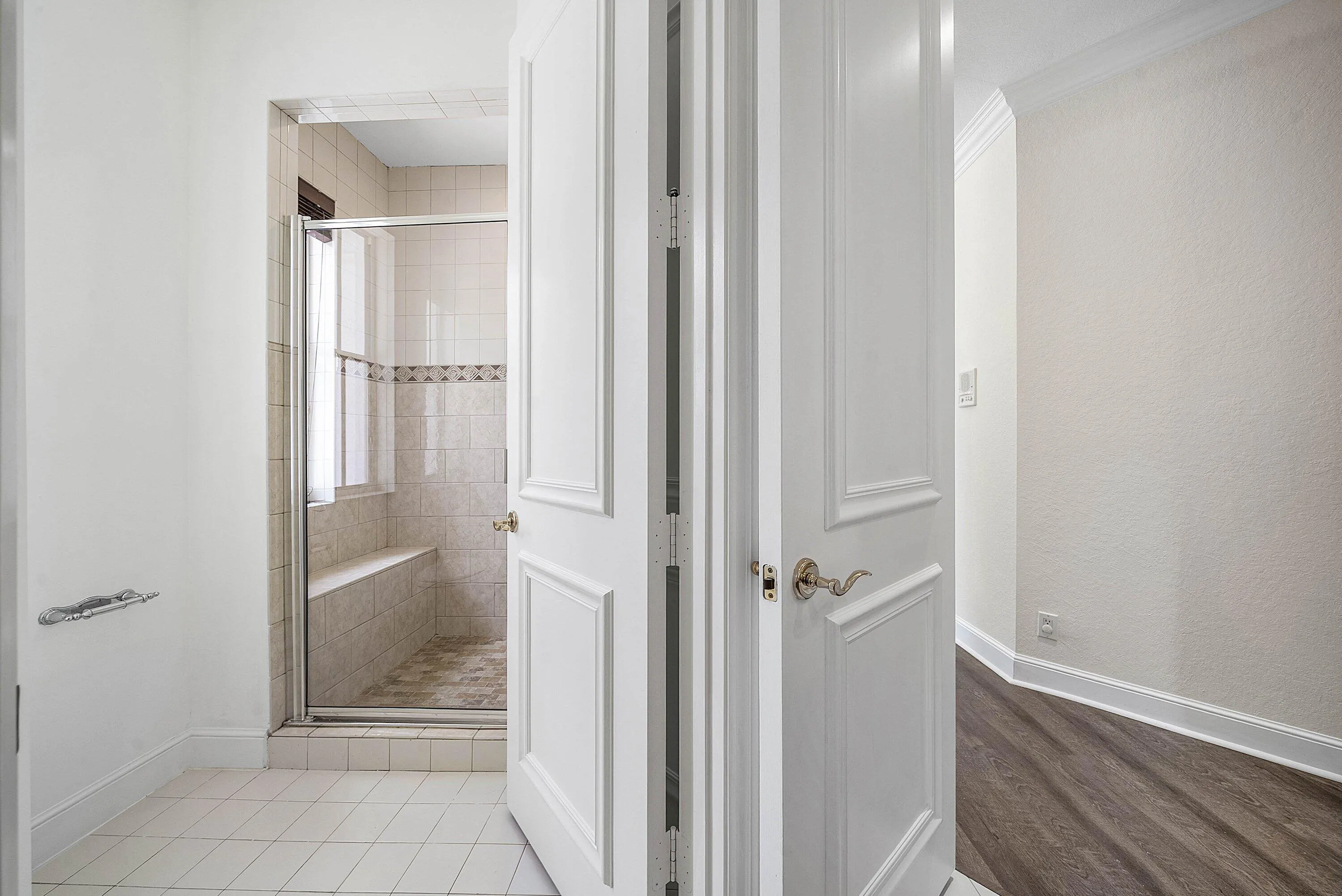 Shower enclosure with a glass door, built-in bench, and tile surround