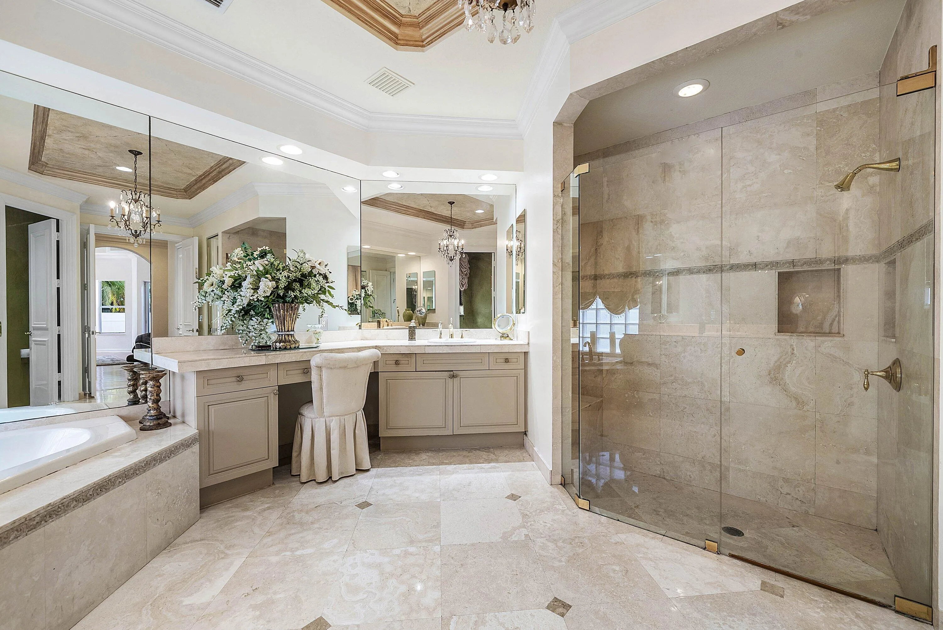 Vanity with ample counter space, integrated makeup area, and large mirrored wall
