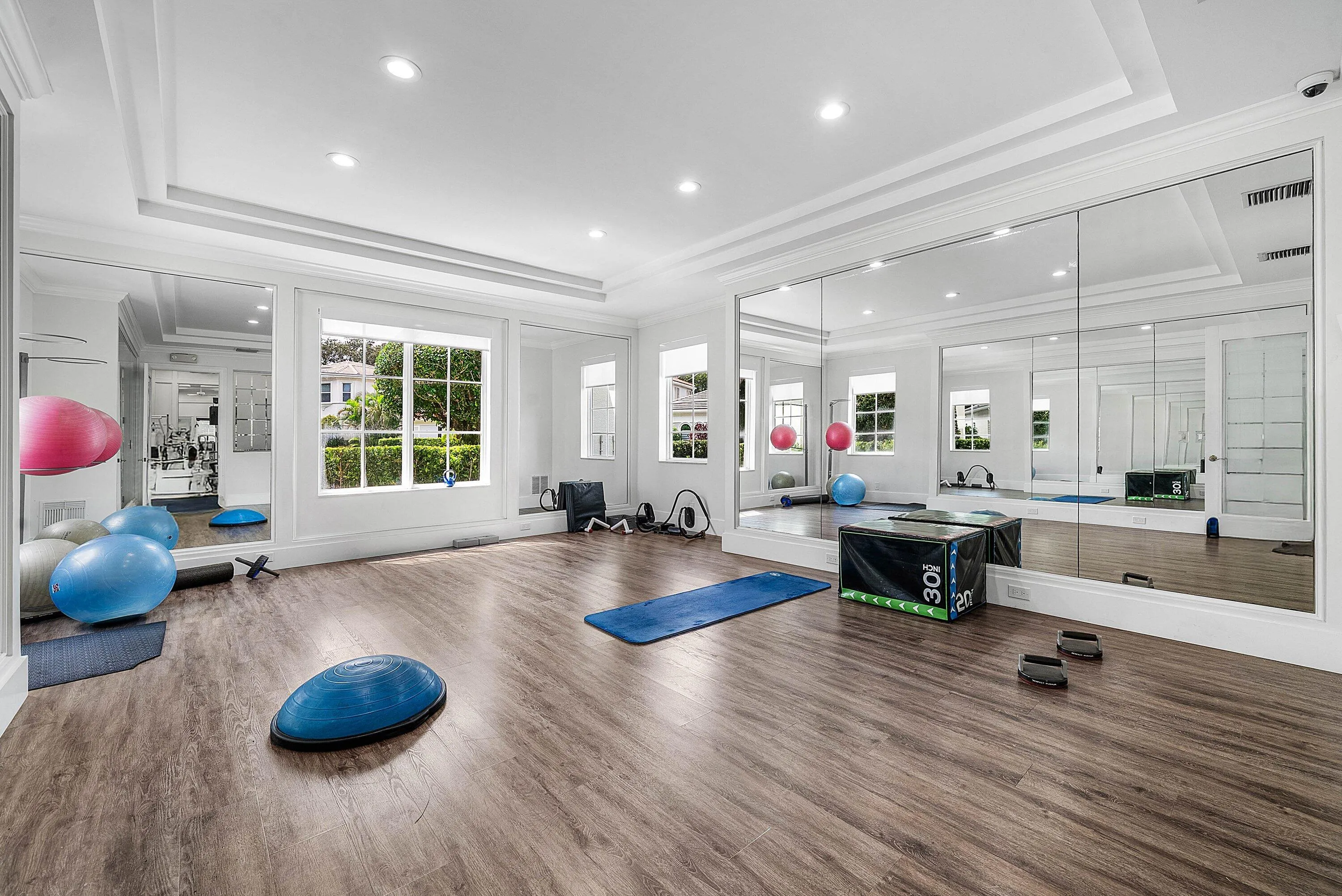Spacious room featuring expansive mirrored wall, tray ceiling - invite your personal trainer