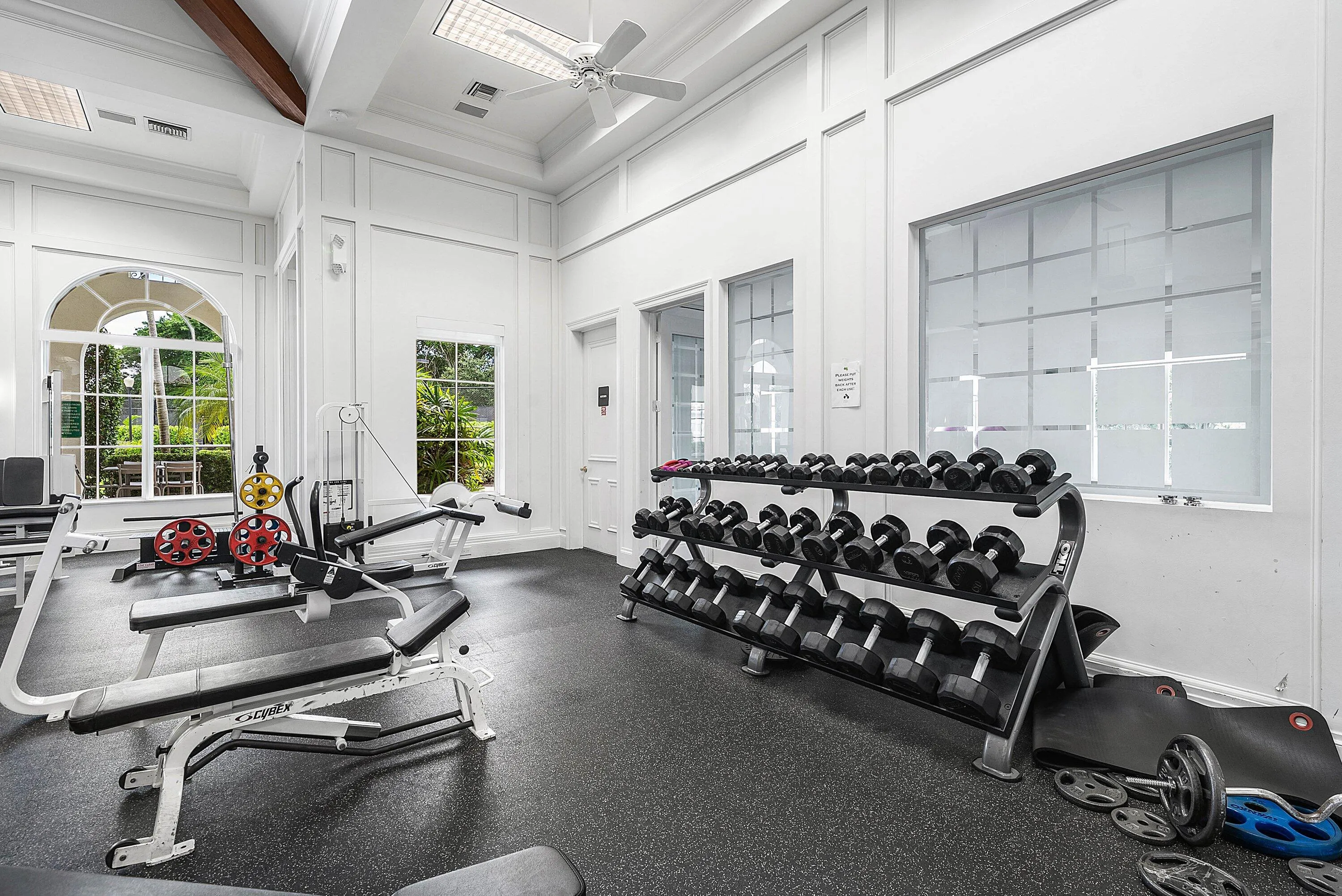 Fitness facility with high vaulted ceilings, architectural wall paneling, large arched windows, and rubberized flooring
