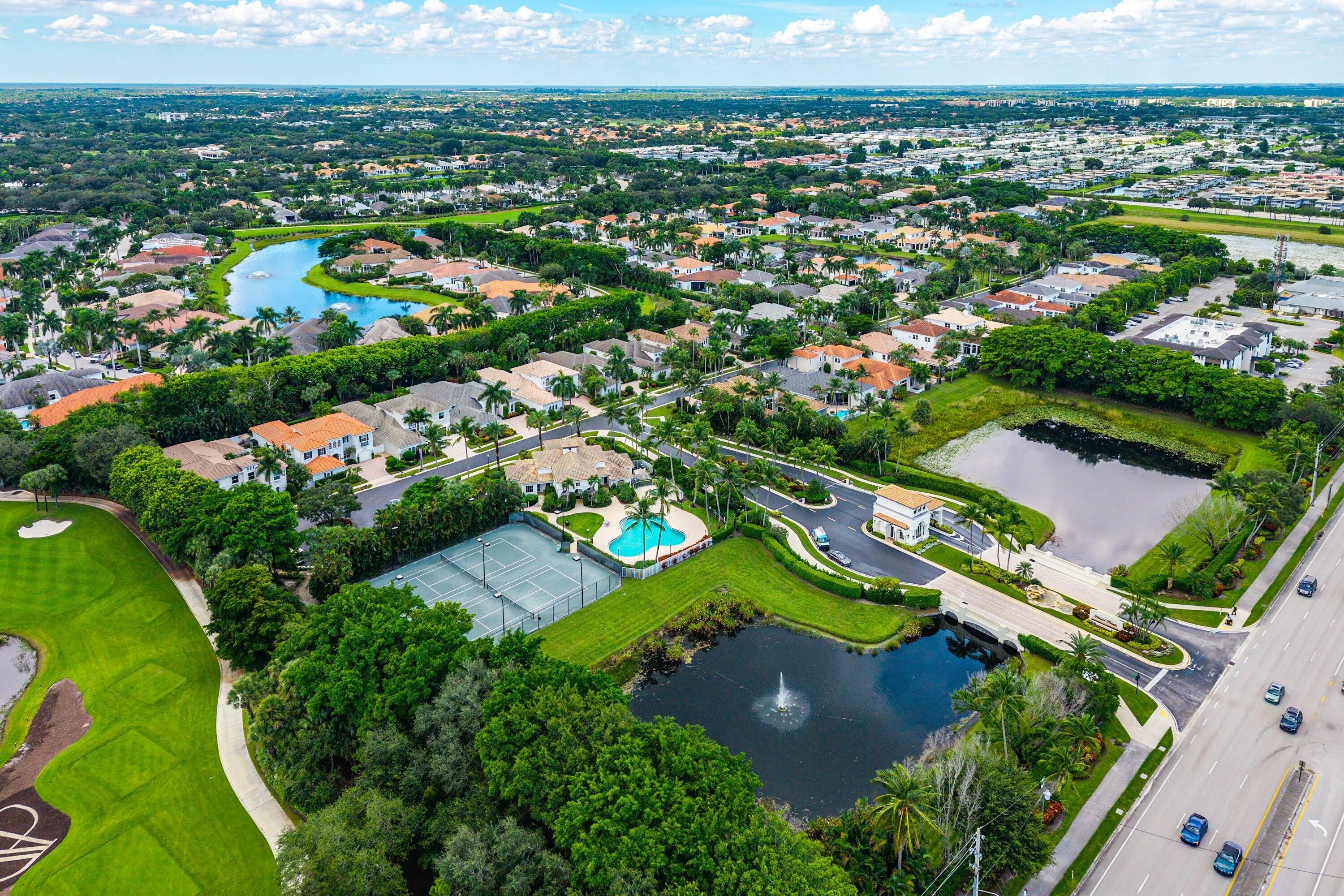 Aerial perspective showcasing a community with mature landscaping, tennis courts, and a swimming pool