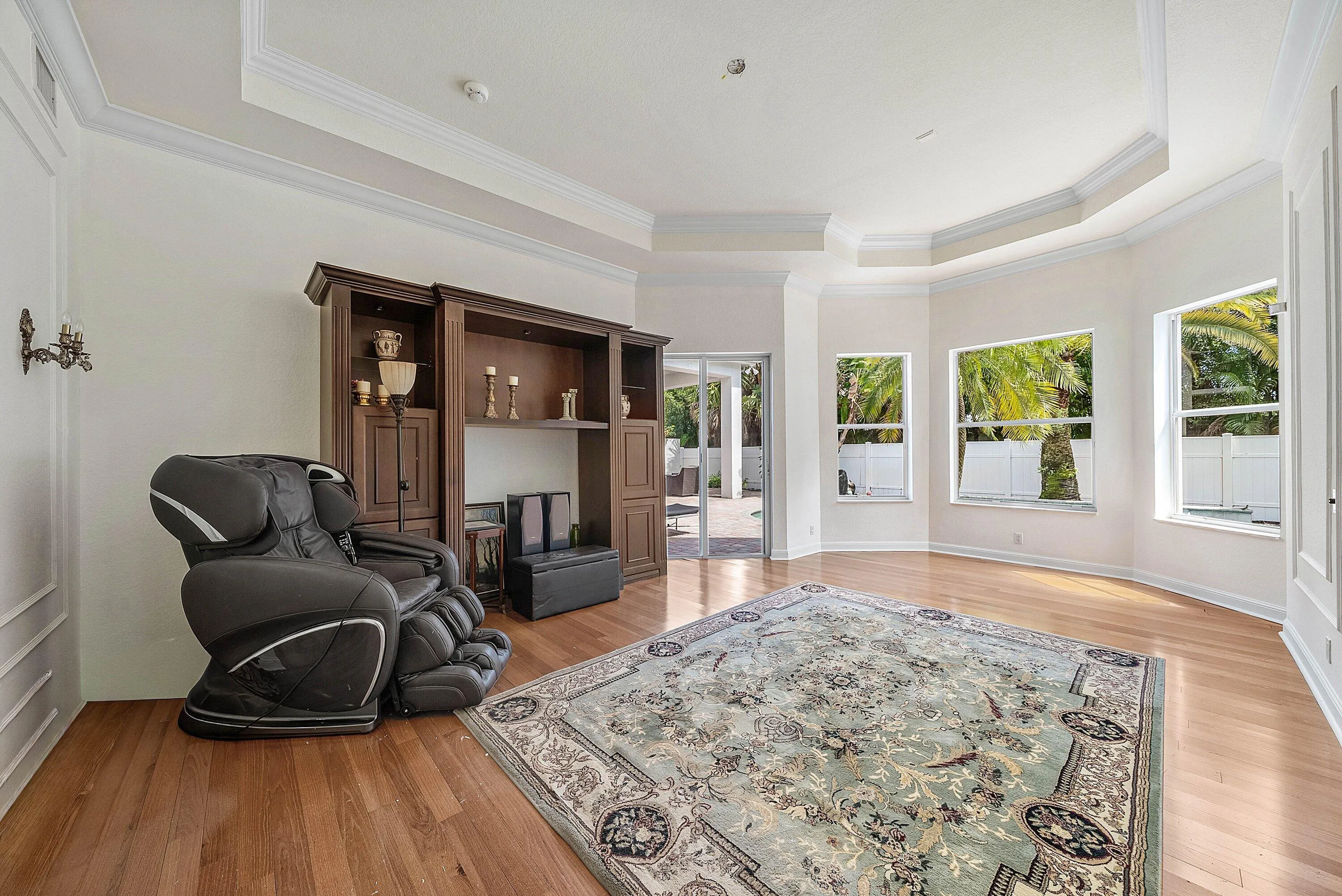 Tray ceiling with crown molding, wood-finish flooring, and a slider door leading to pool/outdoor area