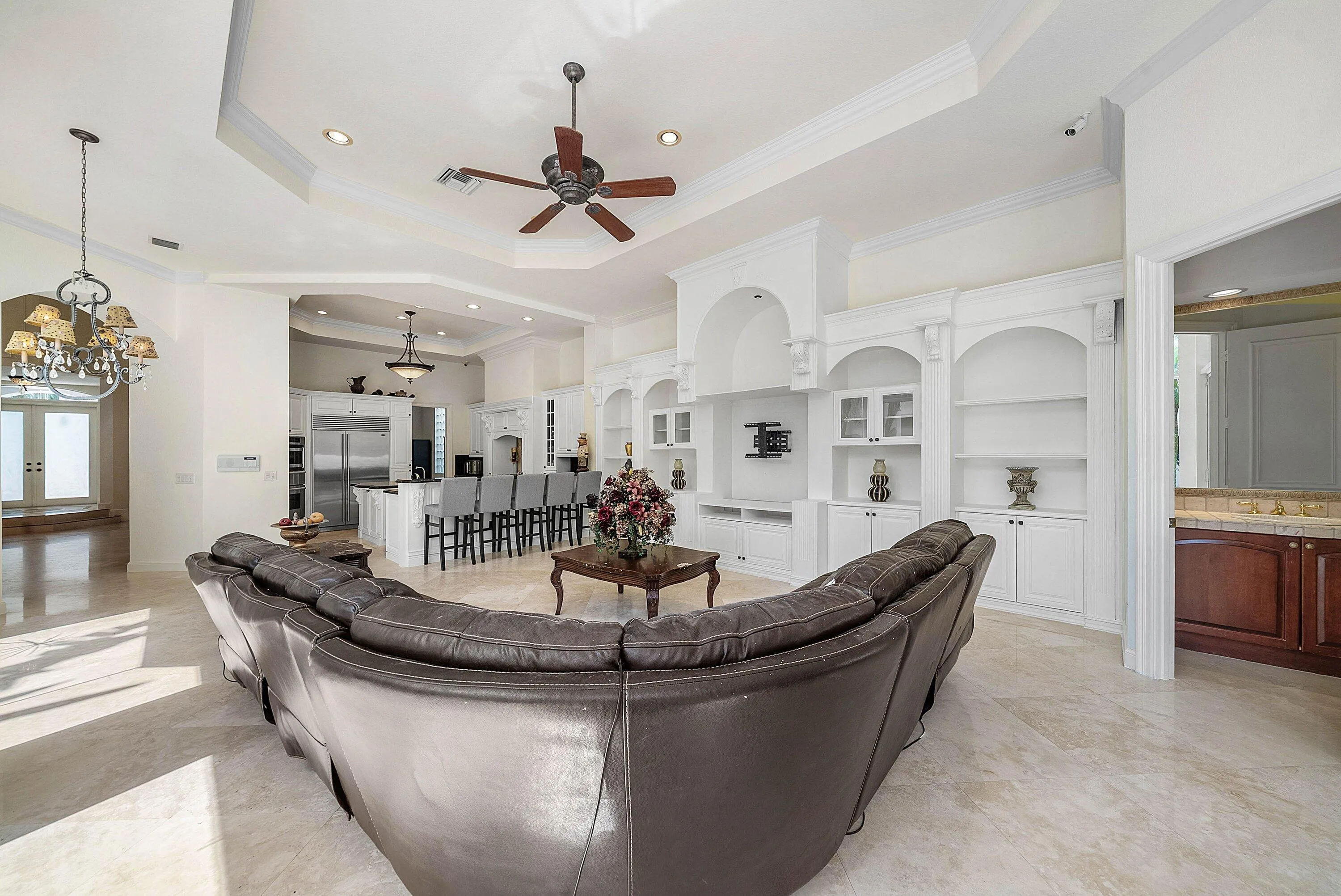 Tray ceilings with recessed lighting, built-in entertainment center, integrated shelving with arched alcoves.