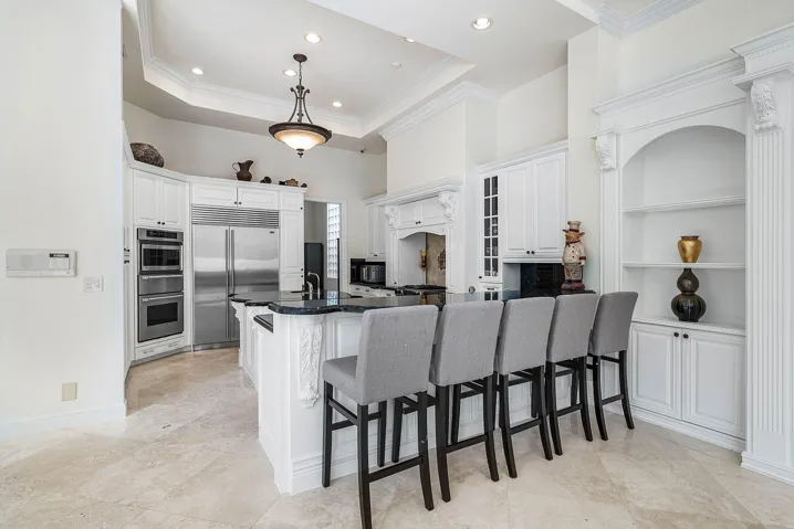 Gourmet kitchen with stainless steel appliances, white cabinetry, granite countertops, a large island with seating, and recessed lighting