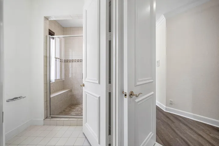 Shower enclosure with a glass door, built-in bench, and tile surround