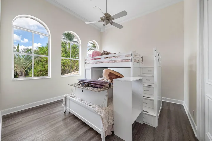Vaulted ceiling with a ceiling fan, arched windows, and wood-finish flooring