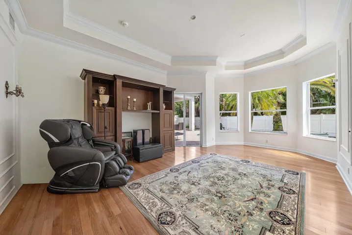 Tray ceiling with crown molding, wood-finish flooring, and a slider door leading to pool/outdoor area