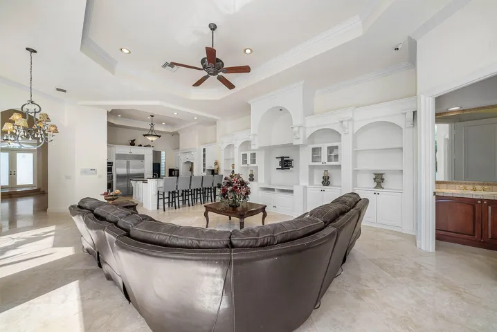 Tray ceilings with recessed lighting, built-in entertainment center, integrated shelving with arched alcoves.