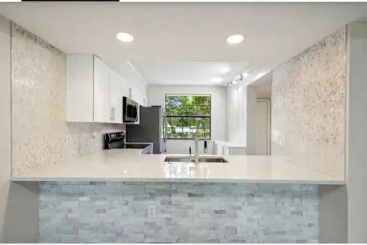Beautiful White kitchen w/ stone wall decor